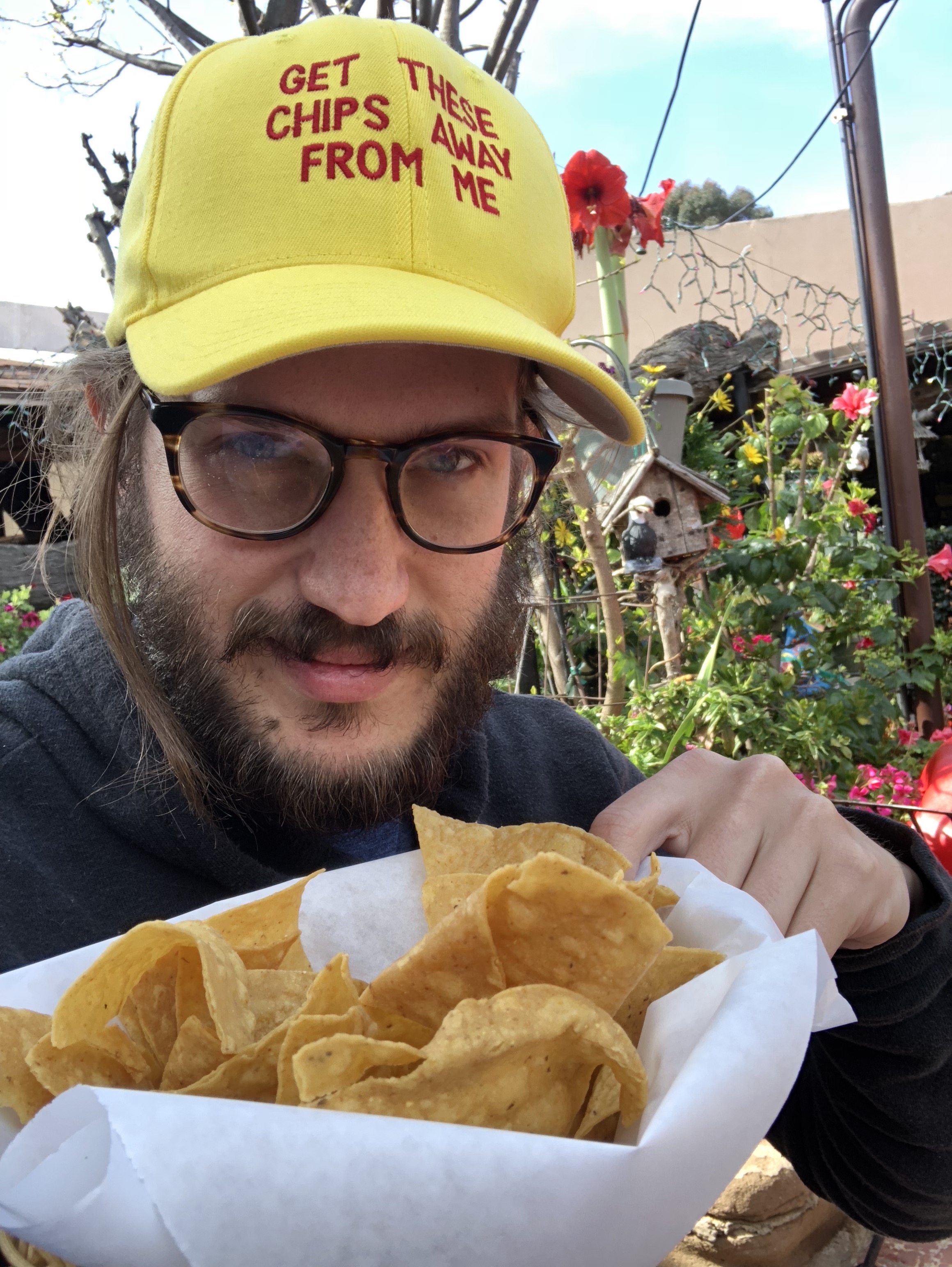 Dana wearing a hat that says "get these chips away from me" with some chips